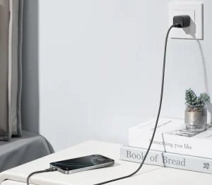 Phone charging on a white table from a wall outlet in a room